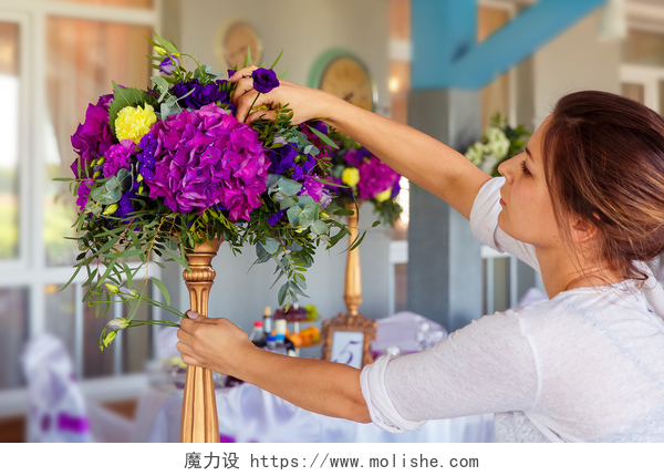女人在往花瓶里面插花在工作的花店。女人做春季花卉装饰韦德